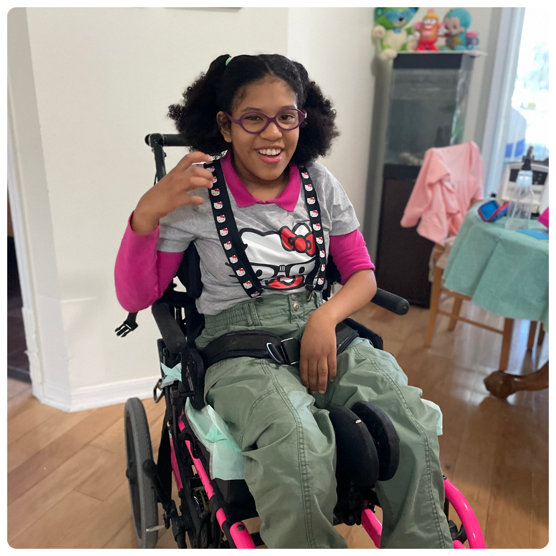 Jadzia smiling. She uses a pink wheelchair and wears Hello Kitty tshirt.