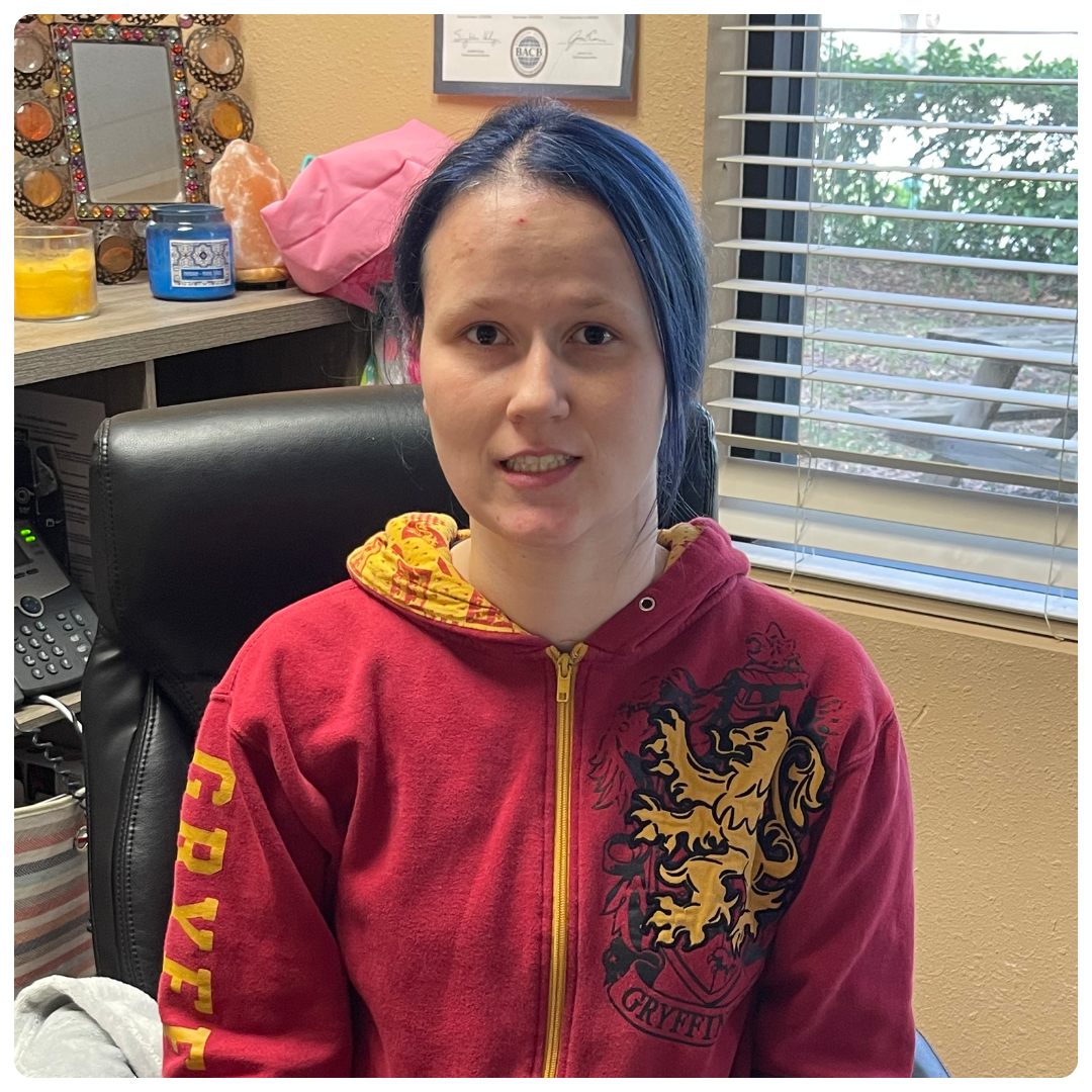 teenage girl with blue hair smiling while wearing a harry potter sweatshirt