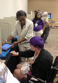 Photograph of a poll worker assisting a voter with a disability.