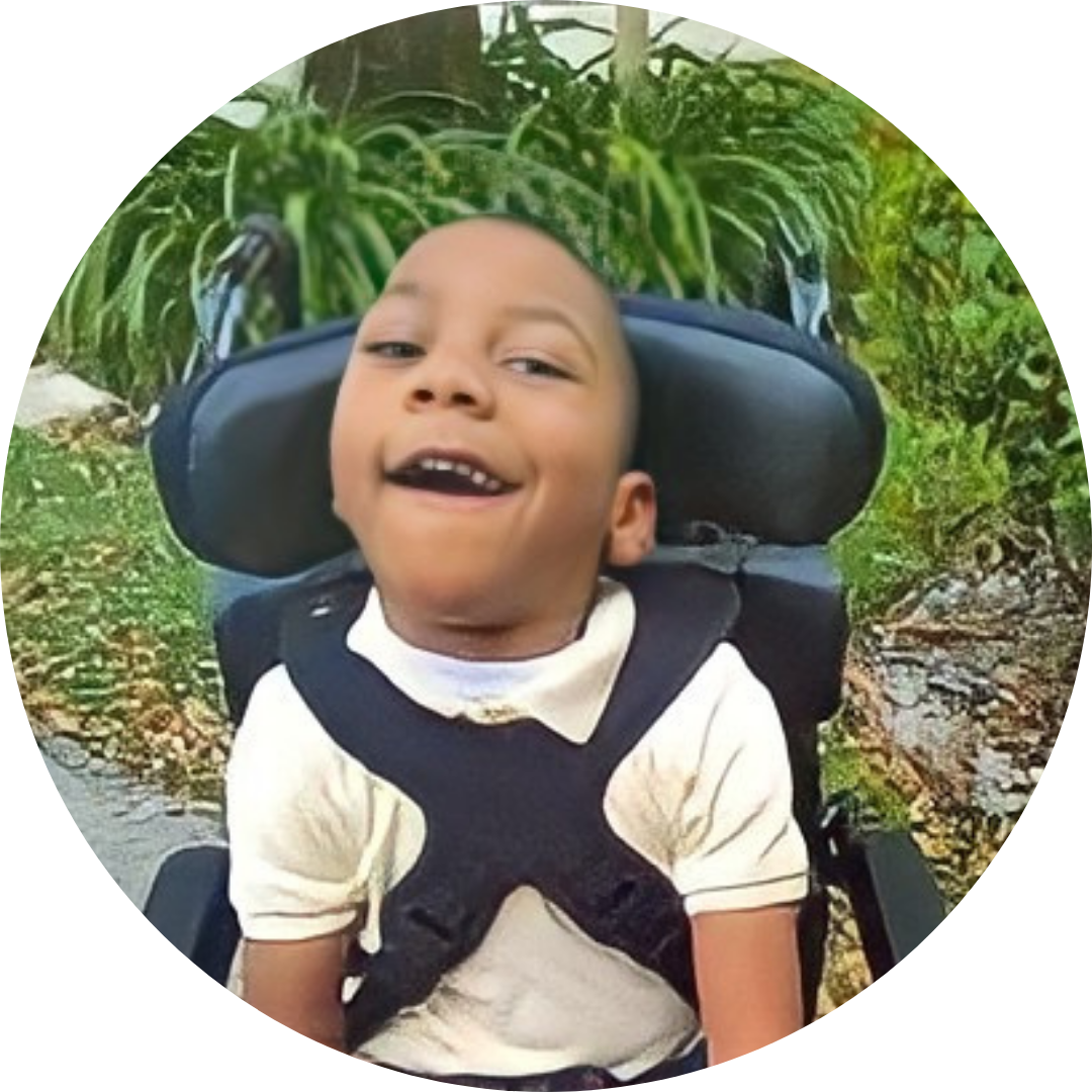 Image of Miraclens. A young boy with a disability. He has dark skin, short hair, and wears a yellow shirt while sitting in his new wheelchair