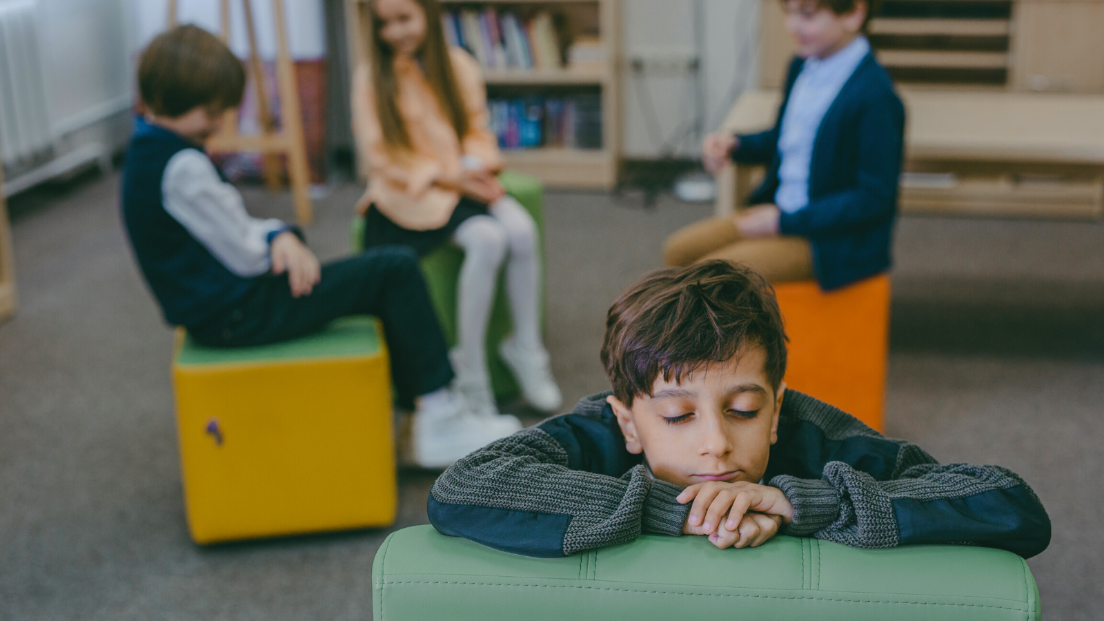 A kid sits alone in a classroom.