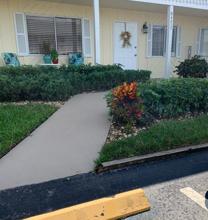 Pathway to yellow building with a walkway. The walkway featured does not have a non-slip path or handrails like client needed.