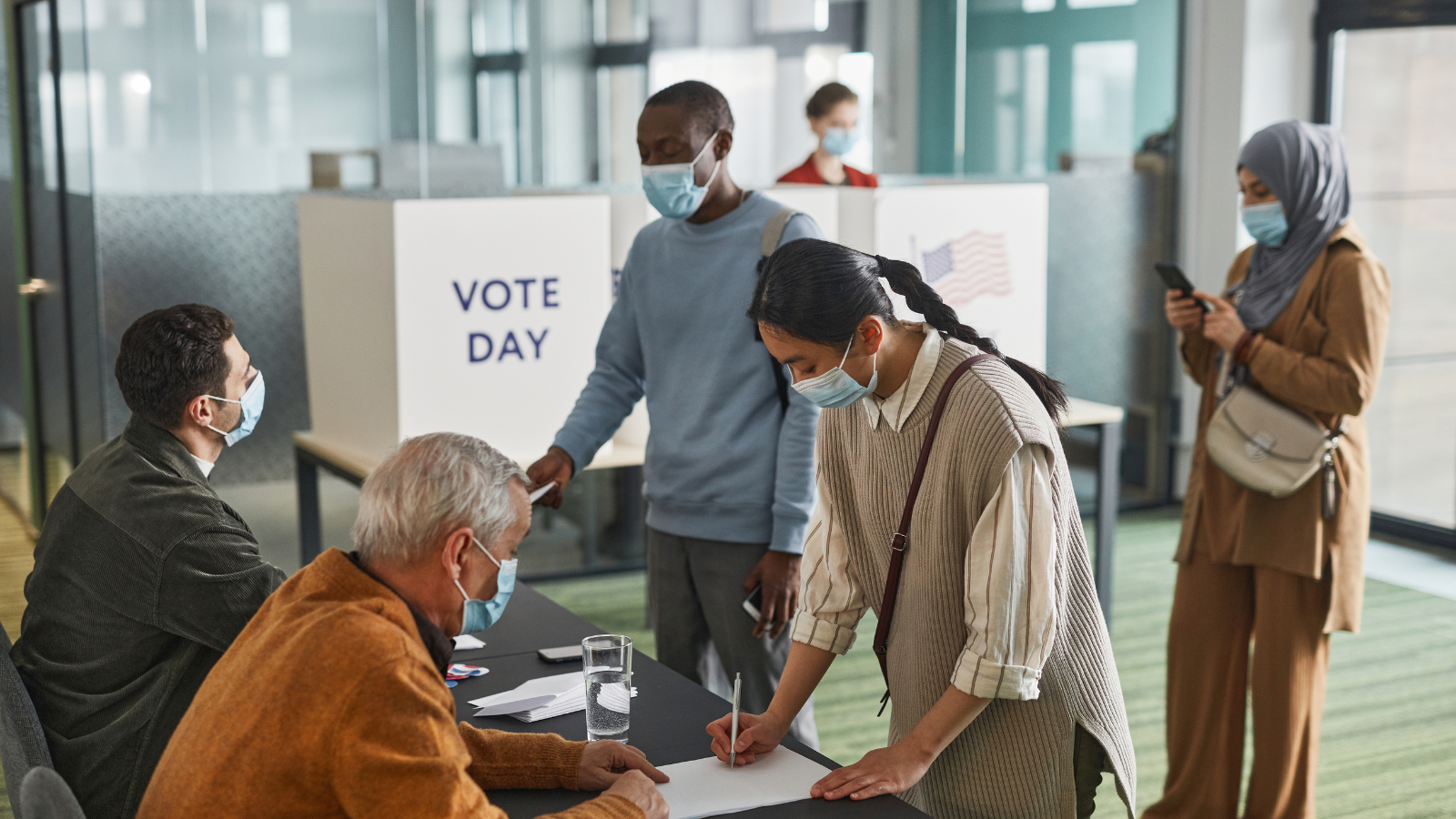 people of diverse backgrounds checking in to vote on election day