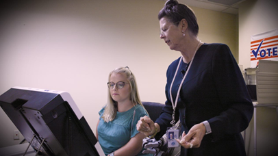 Poll worker assisting woman use accessible voting machine