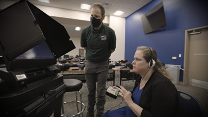 Blind woman using an voting machine's accessible remote option. A poll worker stands by to assist the machine set up.