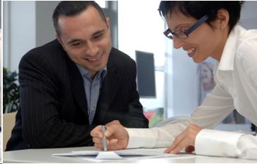 Photograph of two professionals conferring over a document.