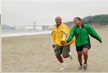 Photograph of a young couple running along the beach.